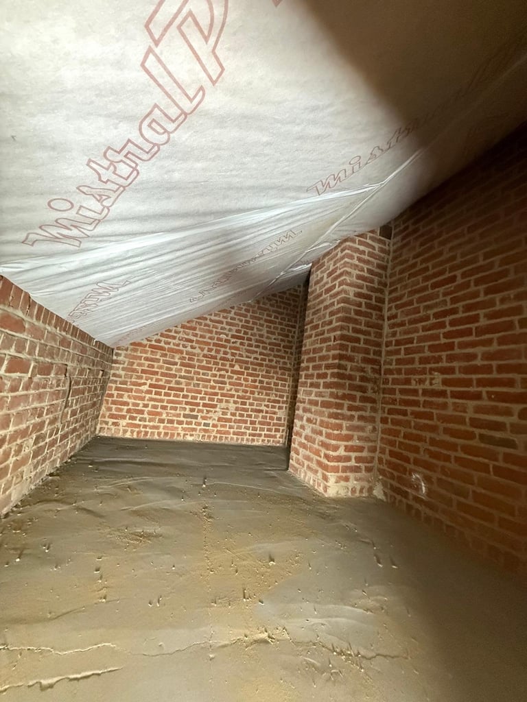 Interior of a brick enclosure with concrete floor and plastic sheeting overhead covering structural supports